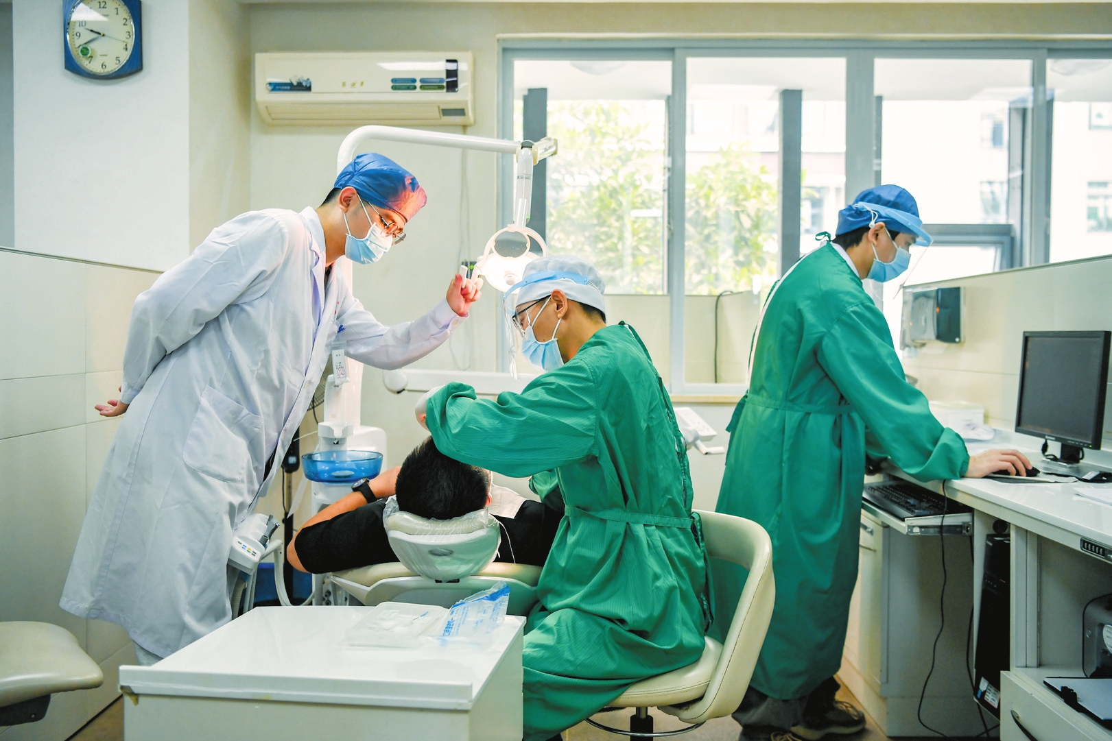 在海口市人民医院口腔医学中心,医生为周末前来就诊的患者检查牙齿